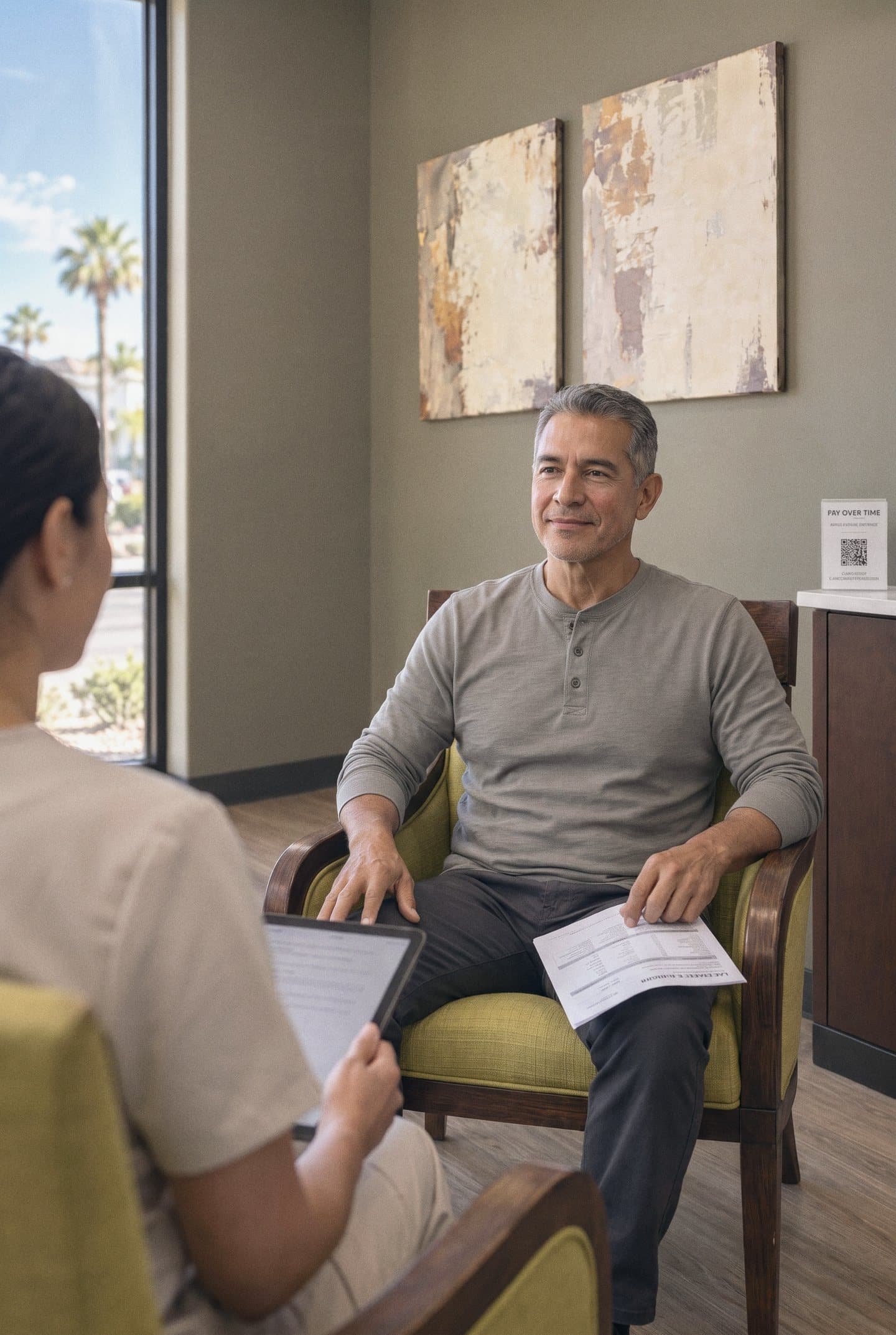 A man holds his lab report while he talks with his nurse practitioner in the consultation room at GIOSTAR Henderson