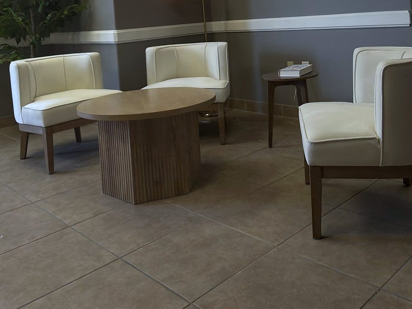 The waiting area at GIOSTAR Henderson, with cream armchairs around a round wood table
