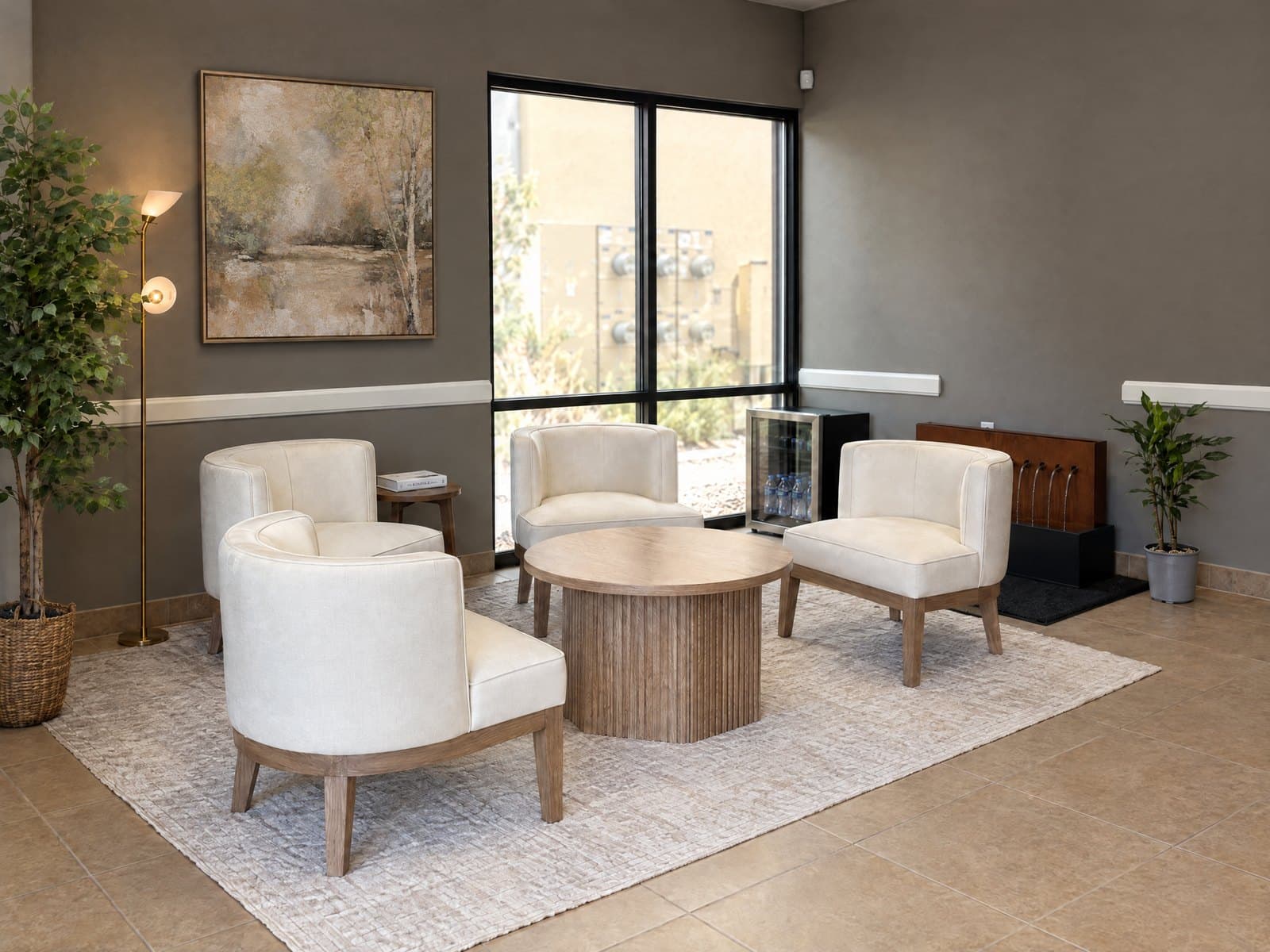 The waiting area at GIOSTAR Henderson, with cream armchairs around a round wood table